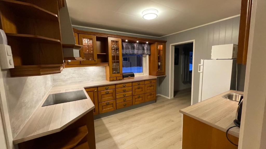 uma cozinha com armários de madeira e um frigorífico branco em Koselig hus i sentrum av Olderfjord em Russenes