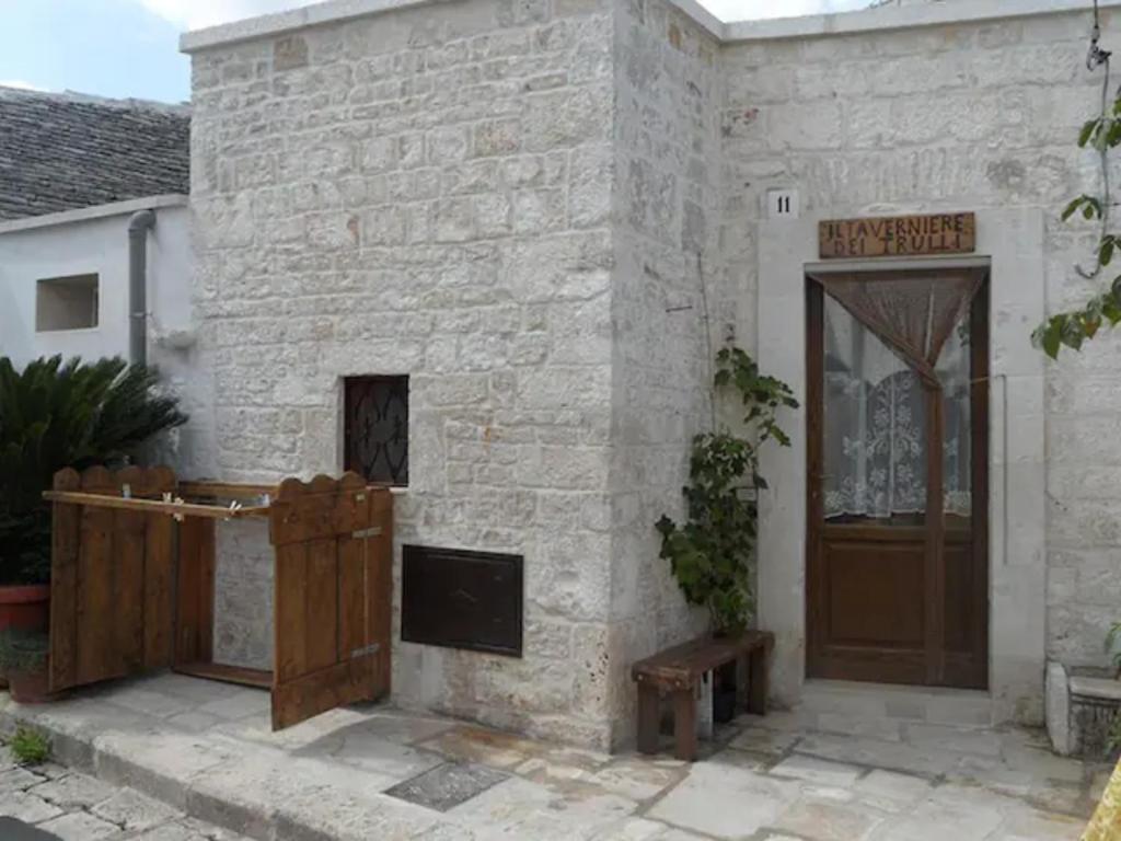 een wit bakstenen gebouw met een houten deur bij Taverniere dei Trulli in Alberobello