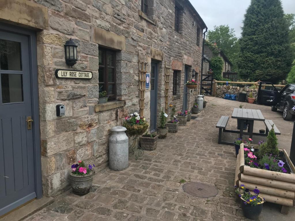 a stone building with a bench and flowers on a street at Waterside Cottages in Waterhouses