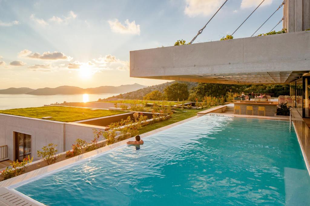 uma piscina no telhado de um edifício com uma pessoa na água em Hotel Osmolis em Zaton