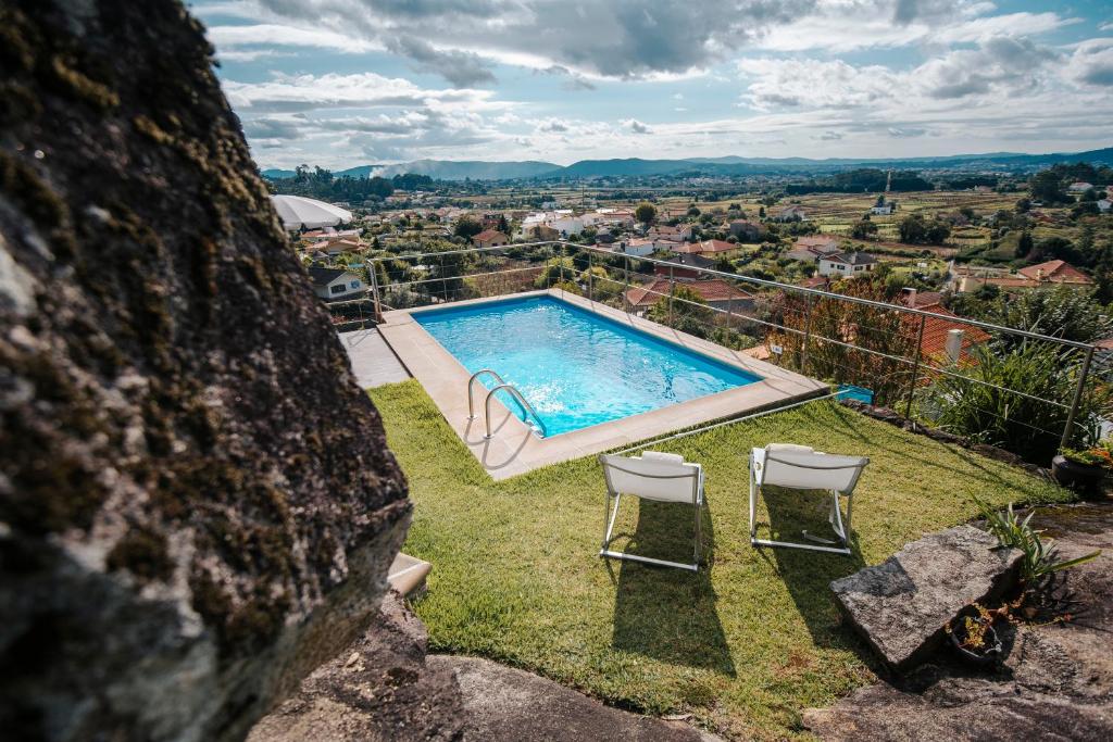a swimming pool on the side of a building with chairs at Casa da Serra in Viana do Castelo
