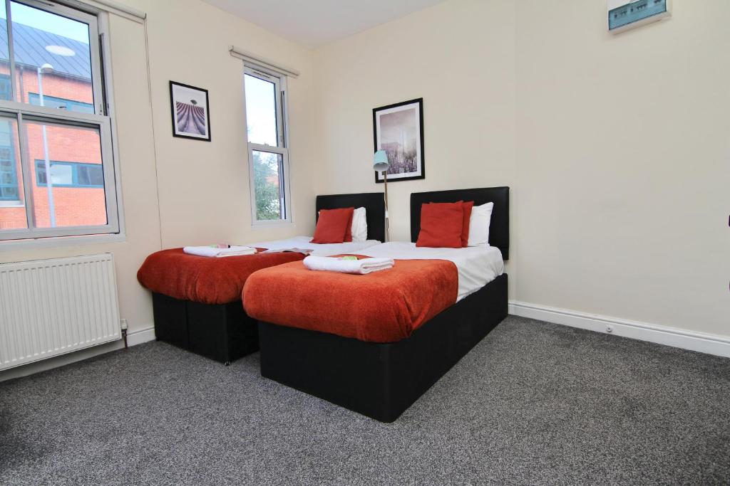 a bedroom with two beds with red pillows at Charming Studio 2 mins Walk To Belgrade Theatre in Coventry