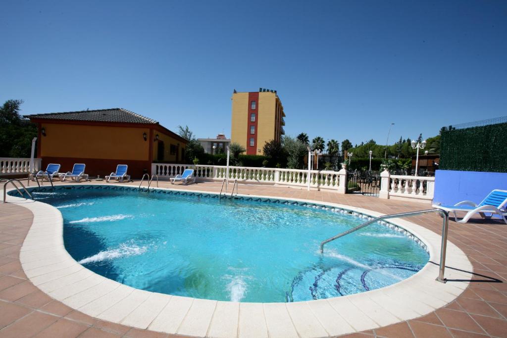 uma grande piscina com cadeiras e um edifício ao fundo em Hotel Zeus em Mérida