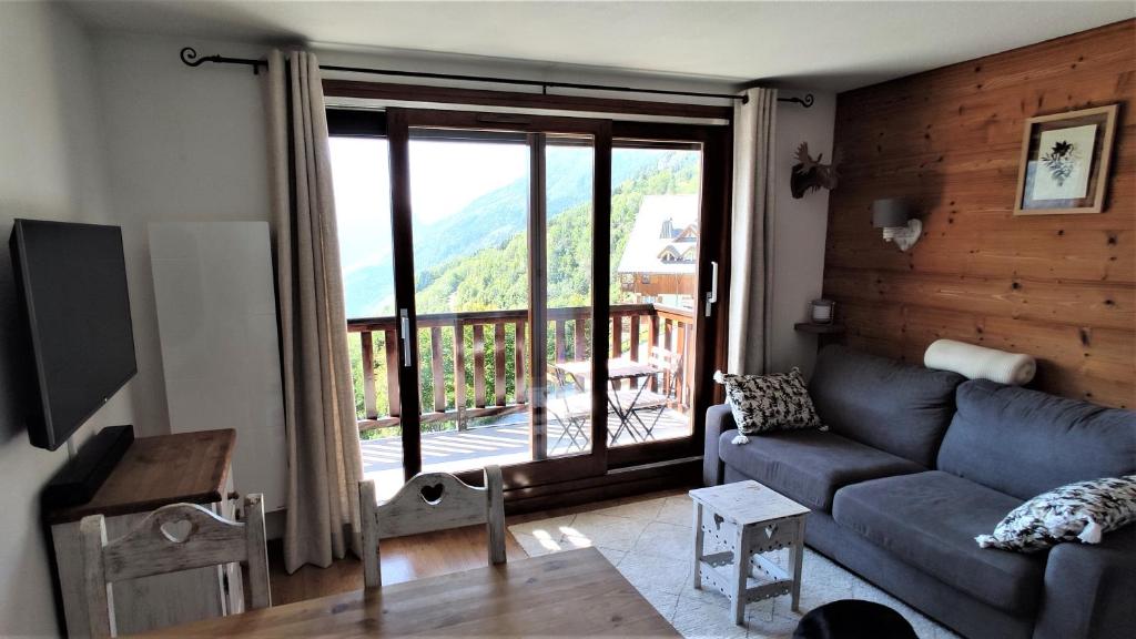 sala de estar con sofá y ventana grande en VAUJANYLOCATIONS - Cochette 1 Studio 9 en Vaujany