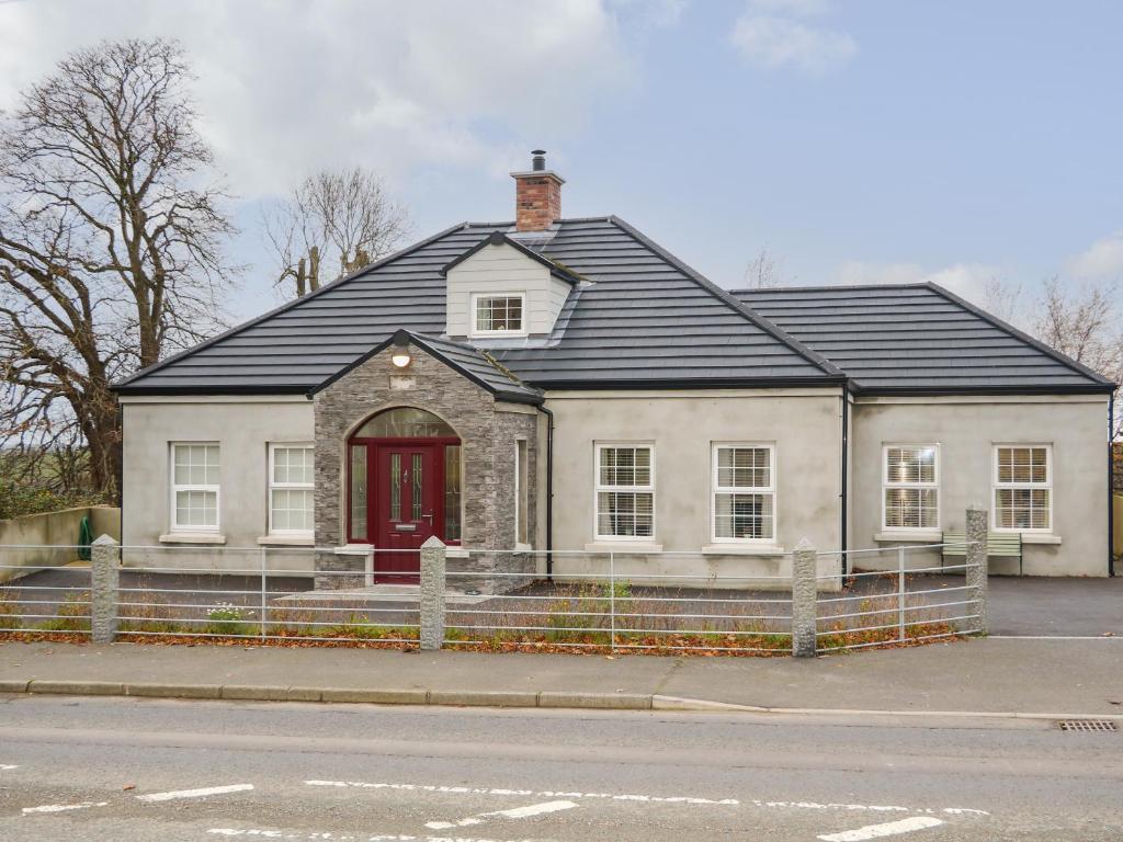 a white house with a red door on a street at Sliabh Amharc in Downpatrick