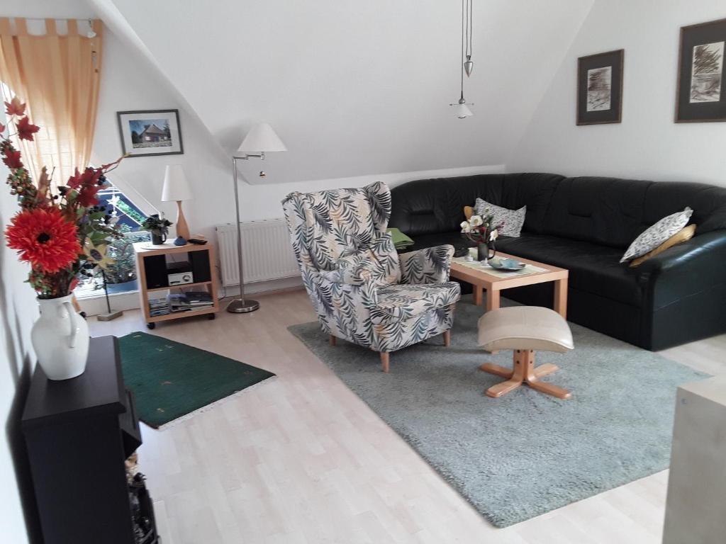 a living room with a black couch and a chair at Birkenstraße 15b Whg 13 in Zingst