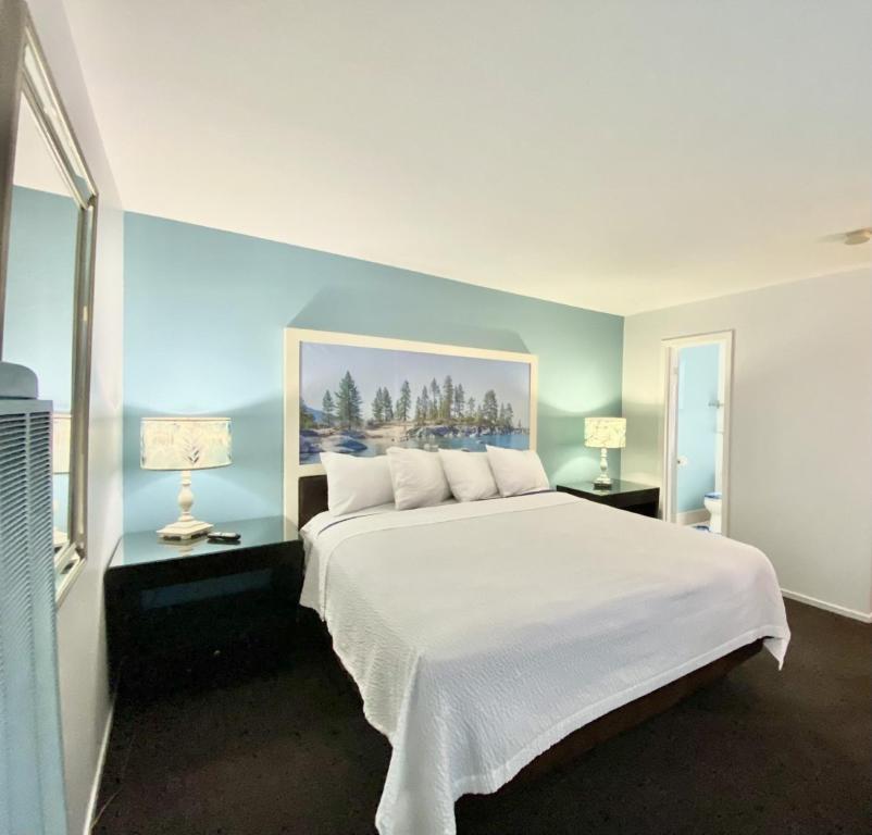 a bedroom with a large white bed with two lamps at Bluebird Day Inn & Suites in South Lake Tahoe