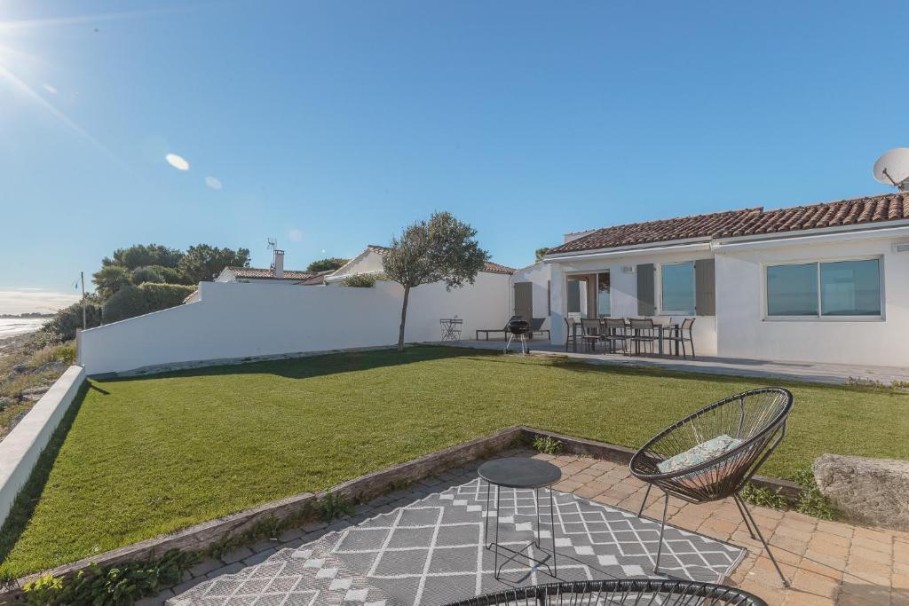 a backyard with a patio with chairs and a lawn at Maison Vue mer panoramique in Rivedoux-Plage