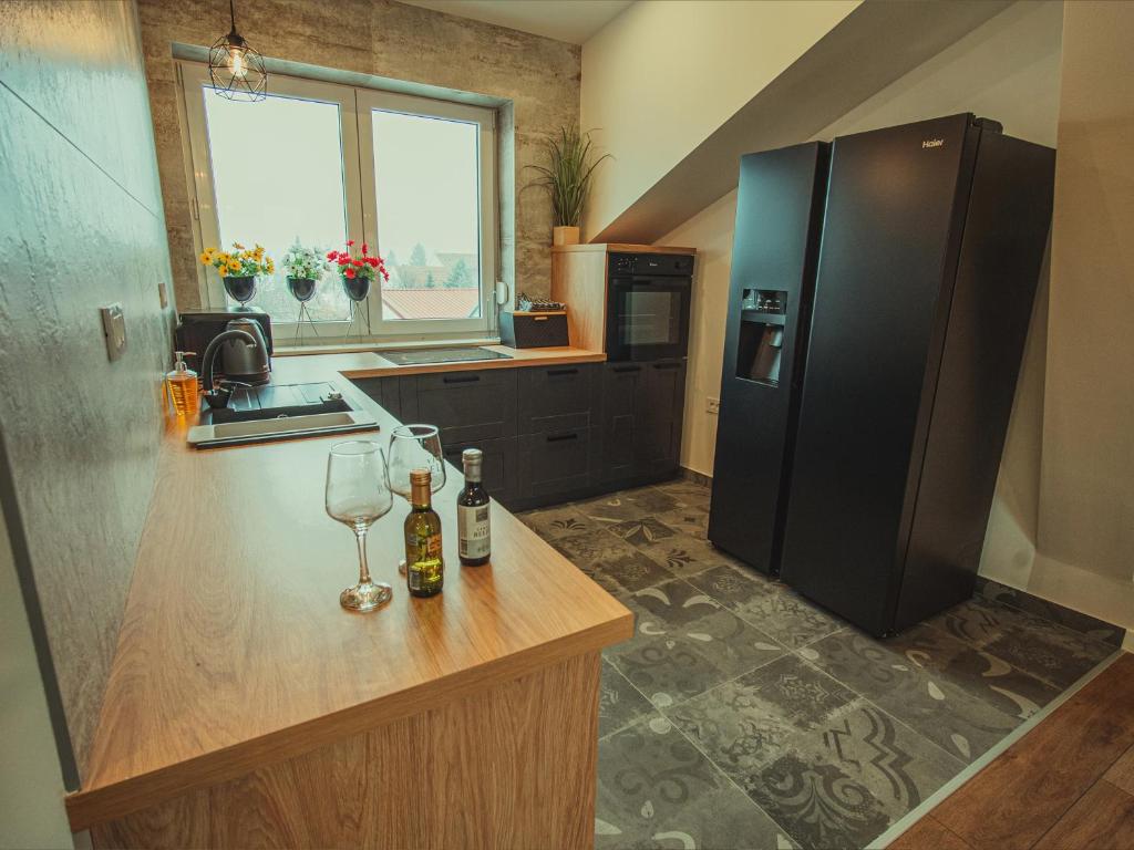 a kitchen with a black refrigerator and a counter with wine glasses at APARTMANI INFINITY in Osijek