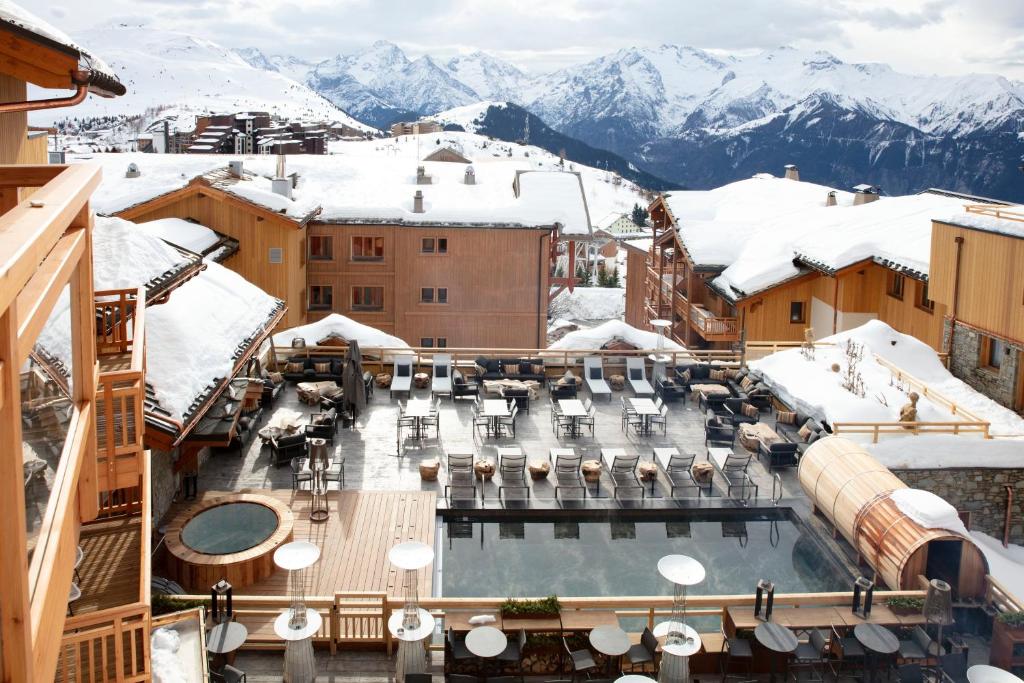 a resort with a pool and snow covered mountains at Grandes Rousses Hotel & Spa in L'Alpe-d'Huez