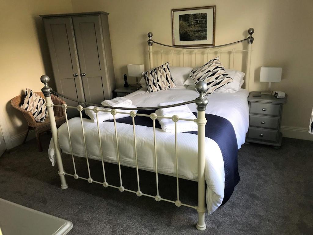 ein Schlafzimmer mit einem großen Bett mit weißen Laken und Kissen in der Unterkunft Bramble Cottage - Luxury Holiday Cottage - 4 Beds 3 Baths - Parking - Beach 1 Mile - Fenced Child & Dog Friendly - EV Chrger in Bude