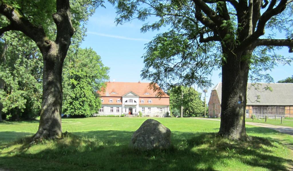 a house with trees and a rock in the grass at Landhotel Gut Zarrentin in Gransebieth