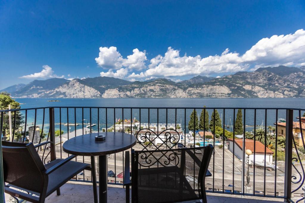 un balcone con tavolo e sedie e vista sull'acqua di APPARTAMENTI CAPRI MALCESINE a Malcesine
