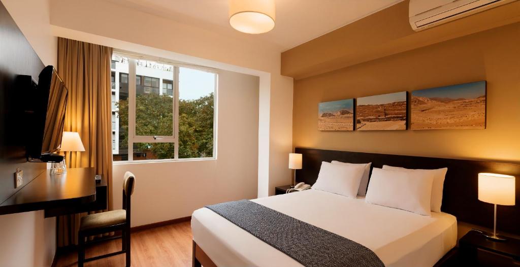 1 dormitorio con cama, escritorio y ventana en Girasoles Hotel, en Lima