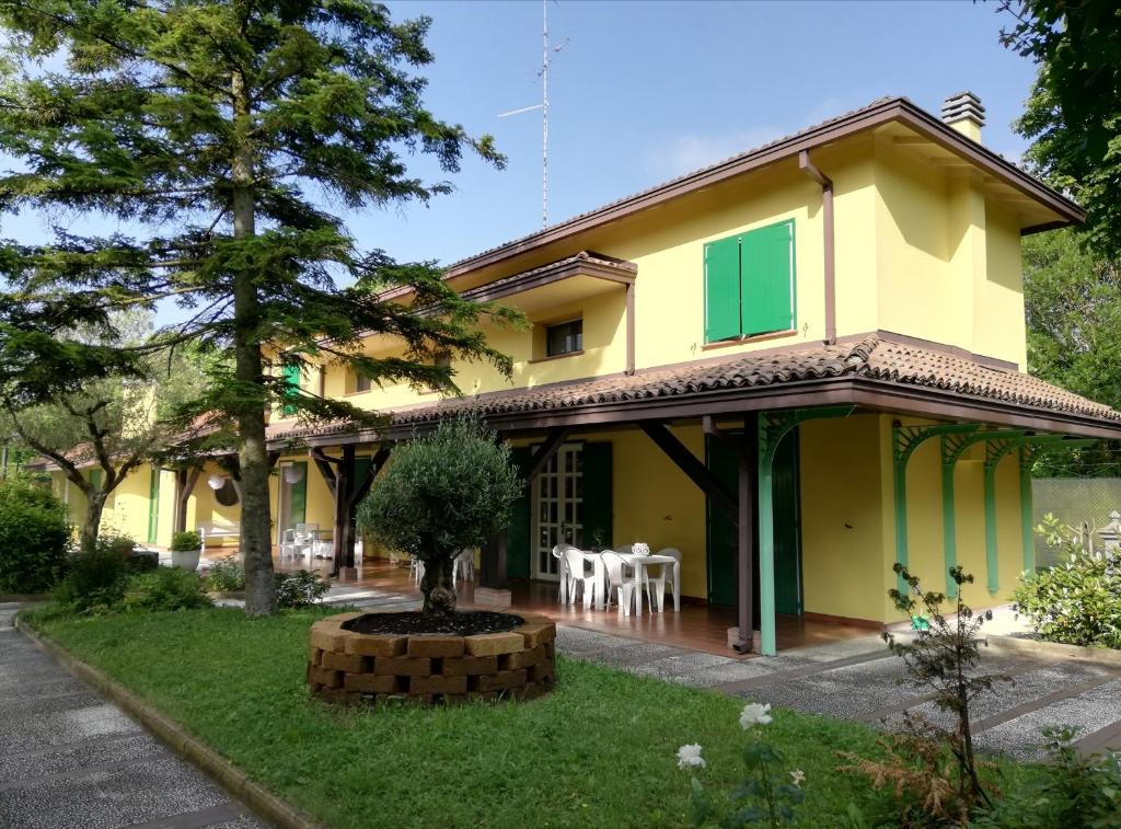 żółty dom z drzewem w ogrodzie w obiekcie B&B Villa dei Cigni Reali w mieście Carpi