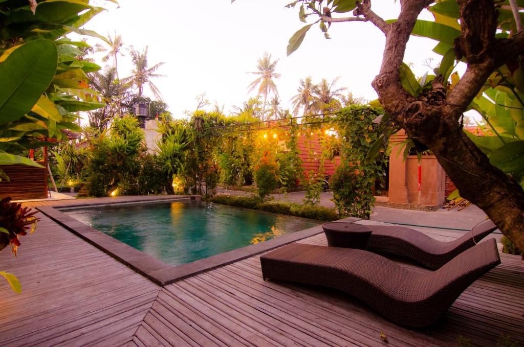 a backyard with a swimming pool and a tree at Kubu Kayana Batuan in Sukawati