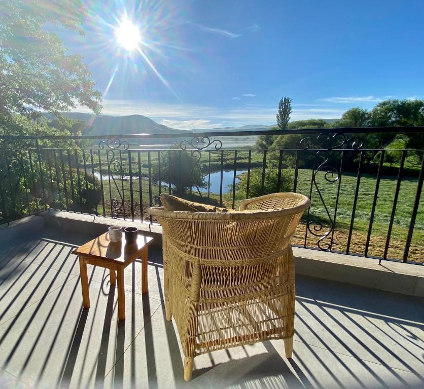 een balkon met een stoel en een tafel en de zon bij Valley Lakes THE LODGE in Underberg