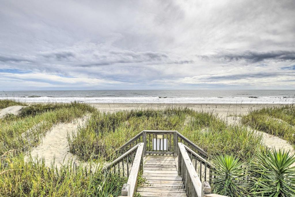 a wooden staircase leading to a beach with the ocean at Cozy Ocean Isle Beach Condo, Steps to the Beach! in Ocean Isle Beach