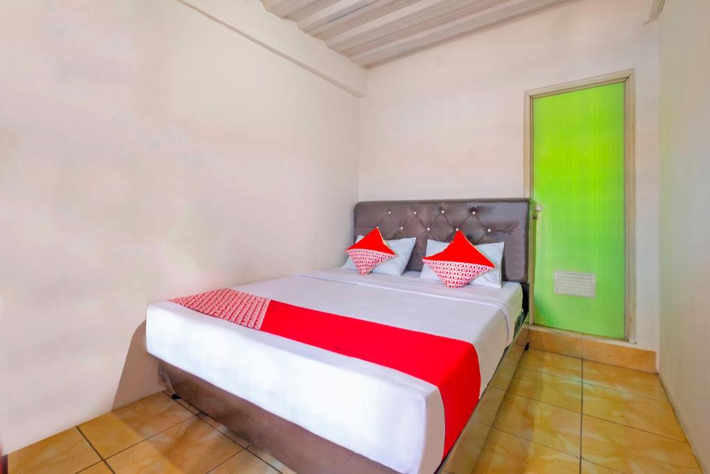 Schlafzimmer mit einem Bett mit roten und grünen Akzenten in der Unterkunft OYO 2562 Pondok Tajlibu Syifa Syariah in Bandung