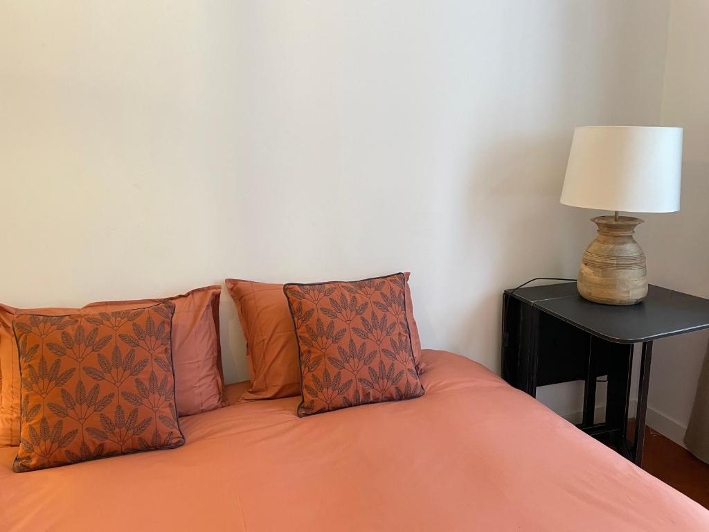 a bed with orange pillows and a lamp on a table at Maison Lligat, appartements dans le centre historique in Perpignan