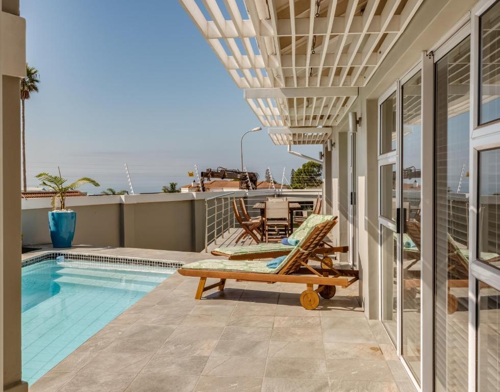 um pátio com uma piscina e cadeiras numa casa em Exclusive Poolside Villa, Humewood em Port Elizabeth
