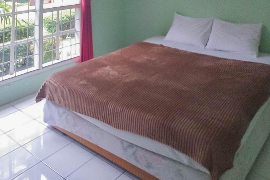 uma cama num quarto com duas janelas em Villa Getsemani Mitra RedDoorz em Sangkanurip