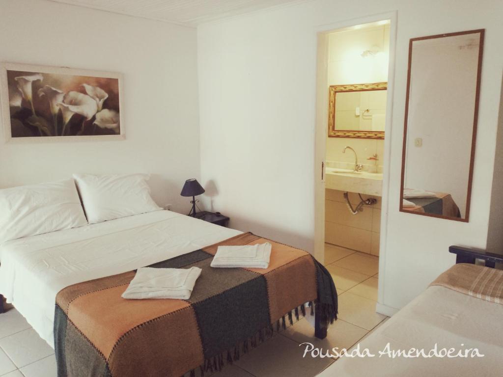1 dormitorio con cama y baño con espejo. en POUSADA AMENDOEIRA, en Búzios