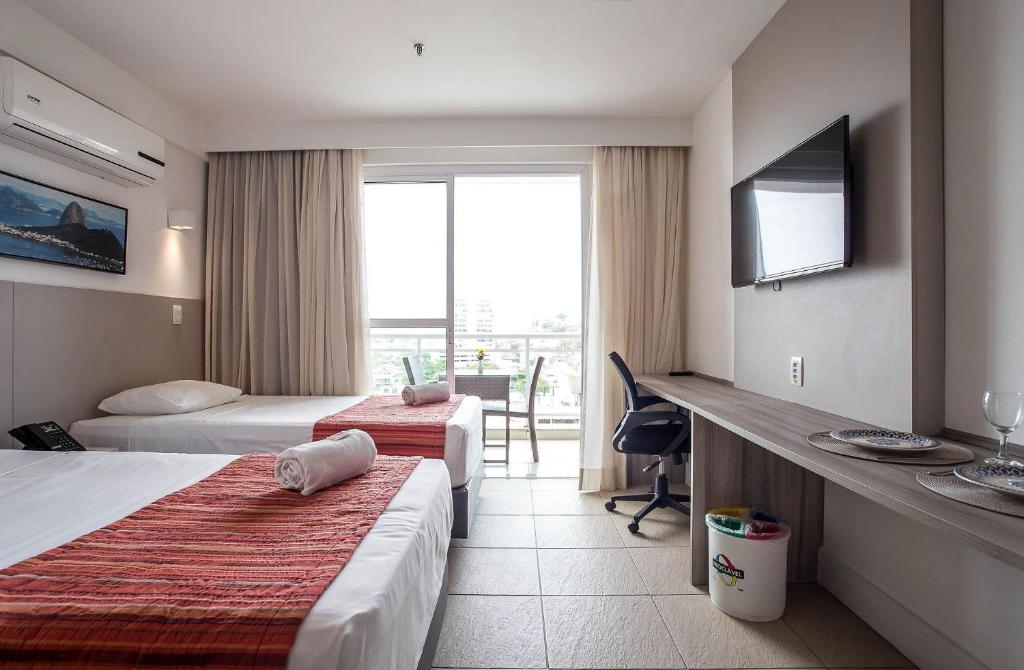 um quarto de hotel com duas camas e uma televisão em Flat 905 - Localização privilegiada em Macaé em Macaé