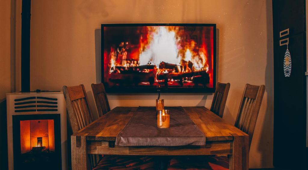 a dining room table with a fire painting on the wall at Incantevole Maisonette nelle Alpi Cuneesi in San Giacomo