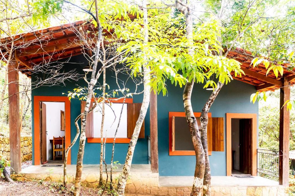 een huis met een blauwe gevel en twee bomen bij Chalé aconchegante com Wi-Fi no Vale do Capão - BA in Vale do Capao