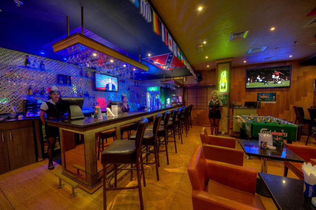 a bar in a restaurant with people standing around it at Fortune Pearl Hotel in Dubai