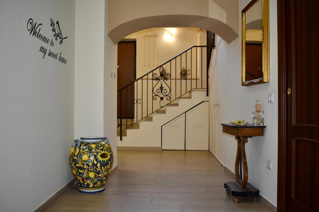 un couloir avec un escalier et un vase au sol dans l'établissement Dimora normanna, à Aversa