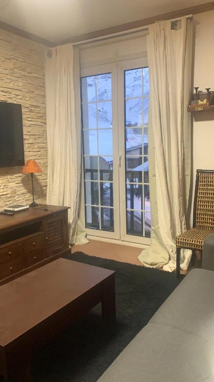 a living room with a large window and a television at Apartamento a pie de pista en edificio Enebro con parking in Sierra Nevada
