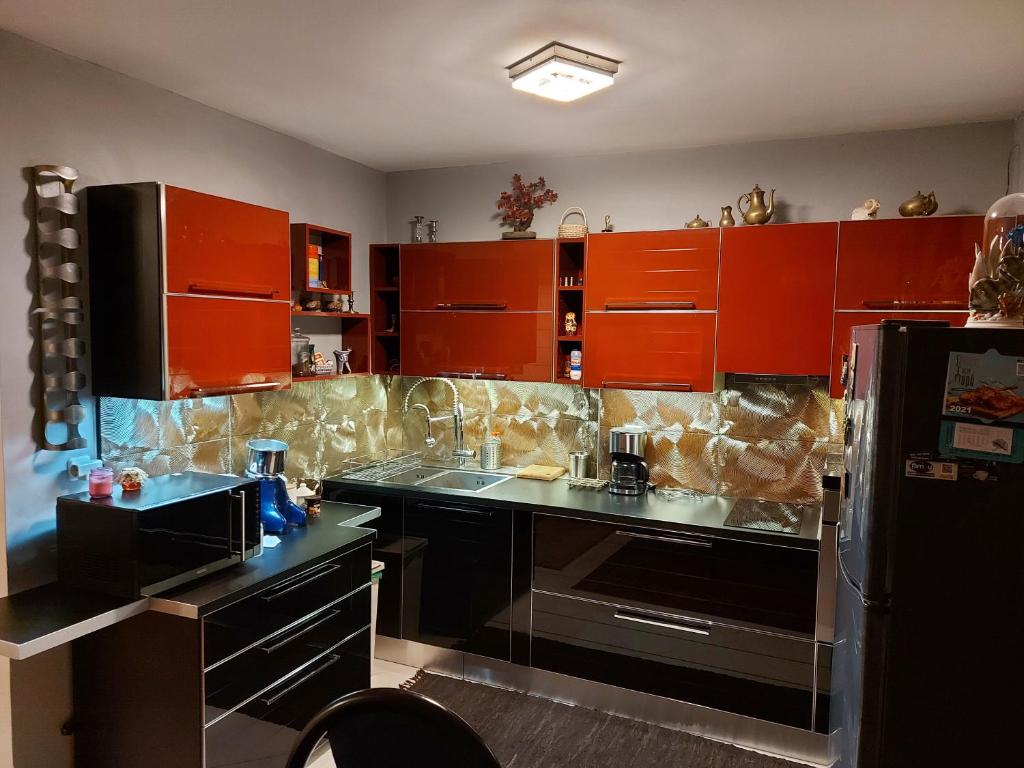 アテネにあるOne bedroom apartment new with large living roomのキッチン(オレンジ色のキャビネット、黒の電化製品付)