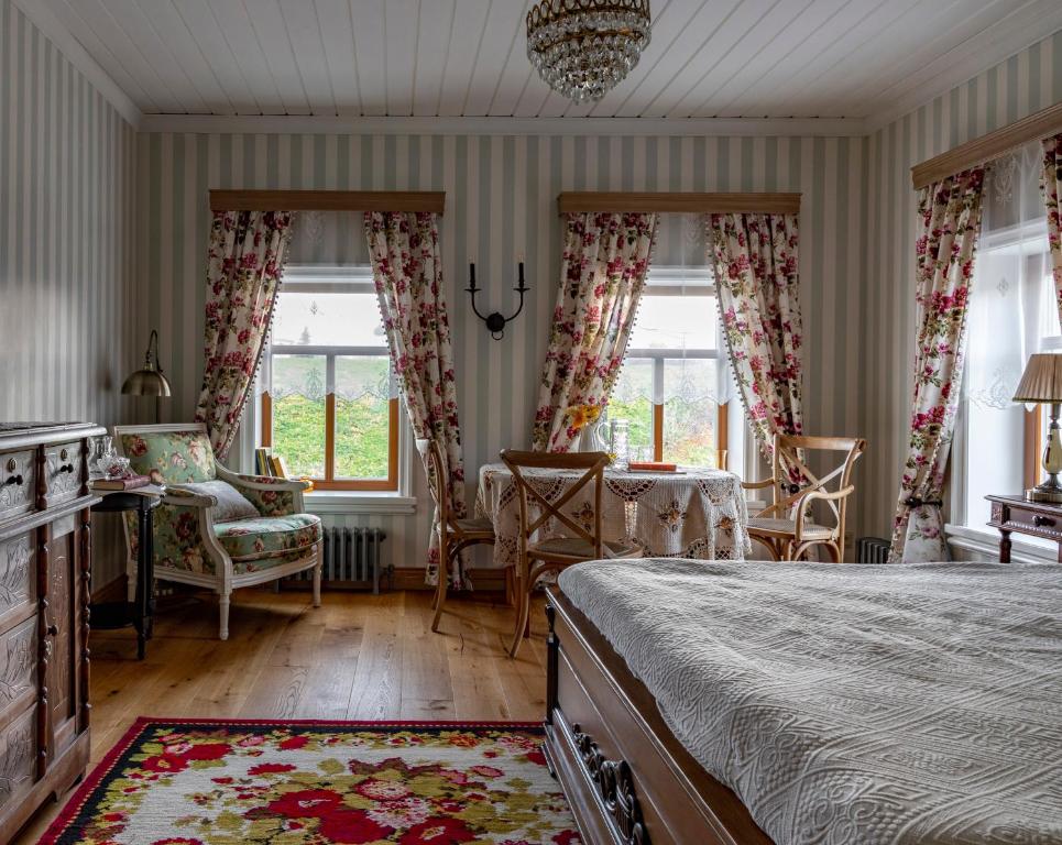 a bedroom with a bed and chairs and windows at Бутик-отель Пестово подворье in Suzdal