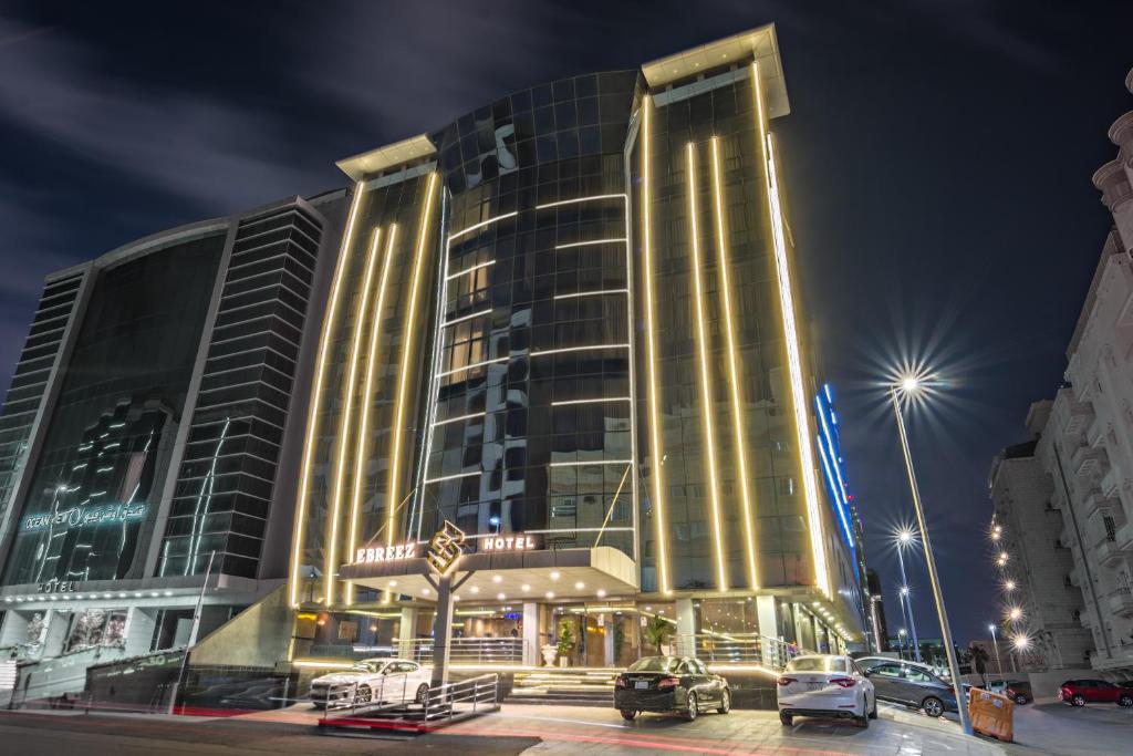 ein großes Gebäude mit Autos auf einem Parkplatz in der Unterkunft Ebreez Hotel in Dschidda