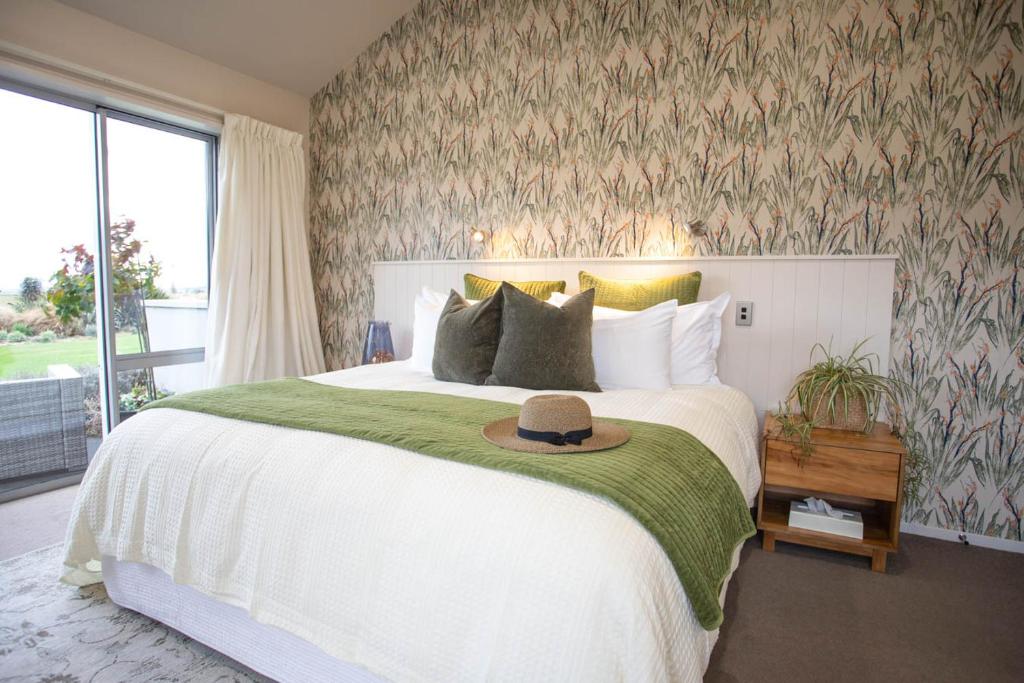 a bedroom with a large bed with a hat on it at Dunluce Boutique B&B in Te Anau