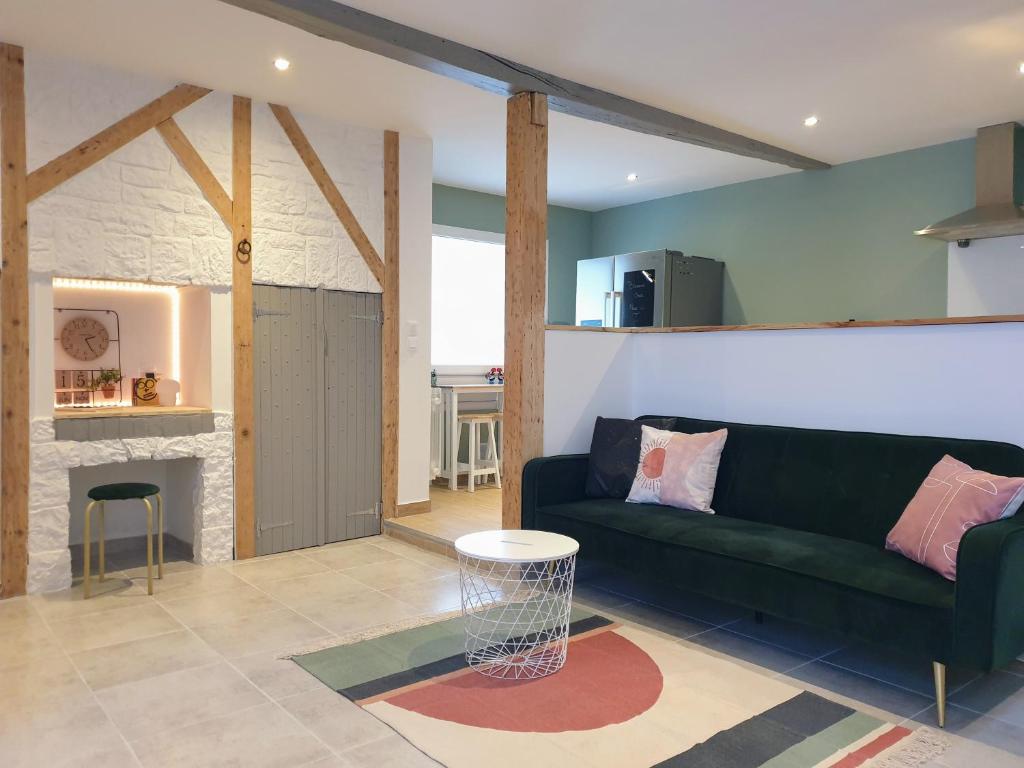 ein Wohnzimmer mit einer grünen Couch und einem Kamin in der Unterkunft Agréable Maison de 72m2, avec terrasse privée in Boeil-Bezing