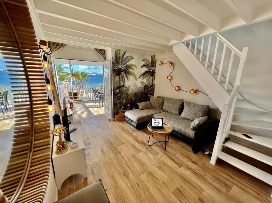 a living room with a staircase and a couch at Duplex JUNGLE BLEUE Terrasse vue mer incroyable in Marigot