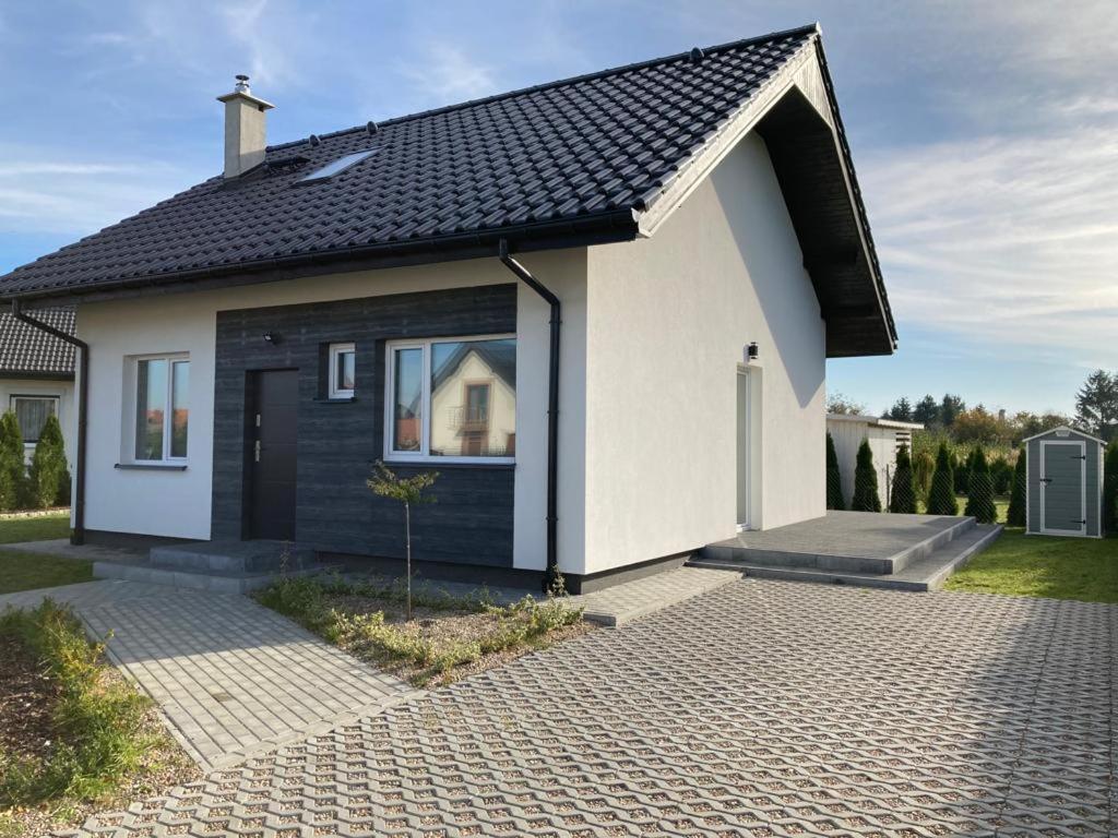 a white and black house with a driveway at Domek in Kamień Pomorski