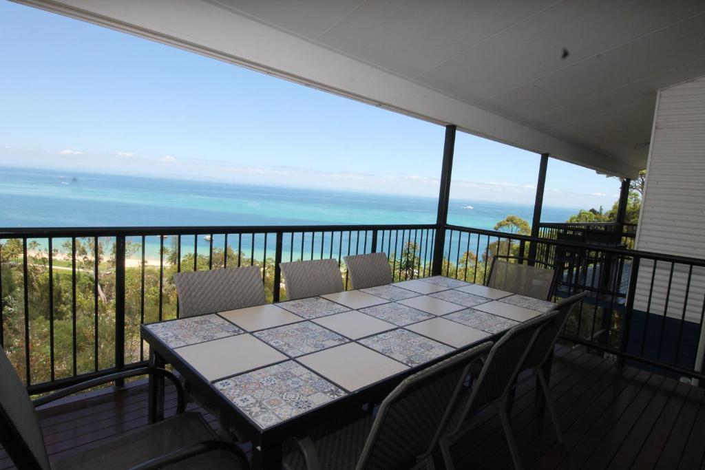 a table on a balcony with a view of the ocean at Nirvana in Tangalooma