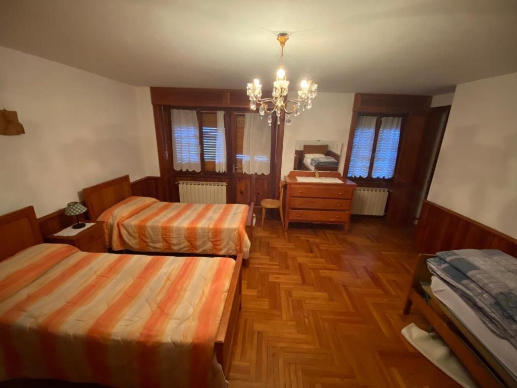 a bedroom with two beds and a desk and a chandelier at Appartamento Proasch in Issime