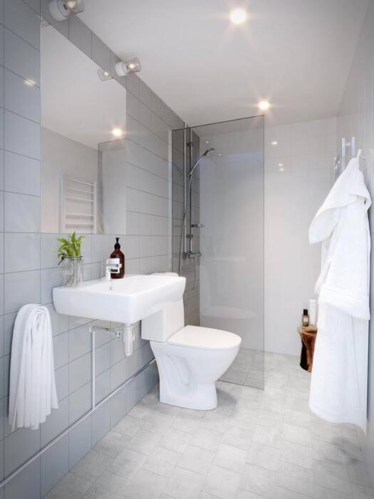 a white bathroom with a sink and a toilet at Avanti Apartment Hotel in Stockholm