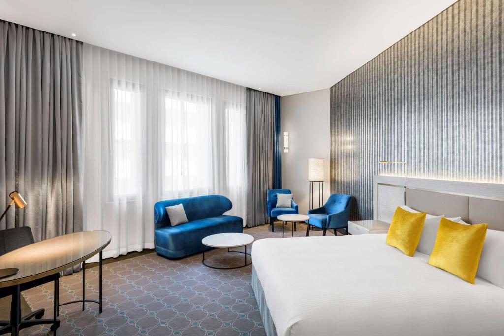 una habitación de hotel con una cama grande y sillas azules en Radisson Blu Plaza Hotel Sydney en Sídney