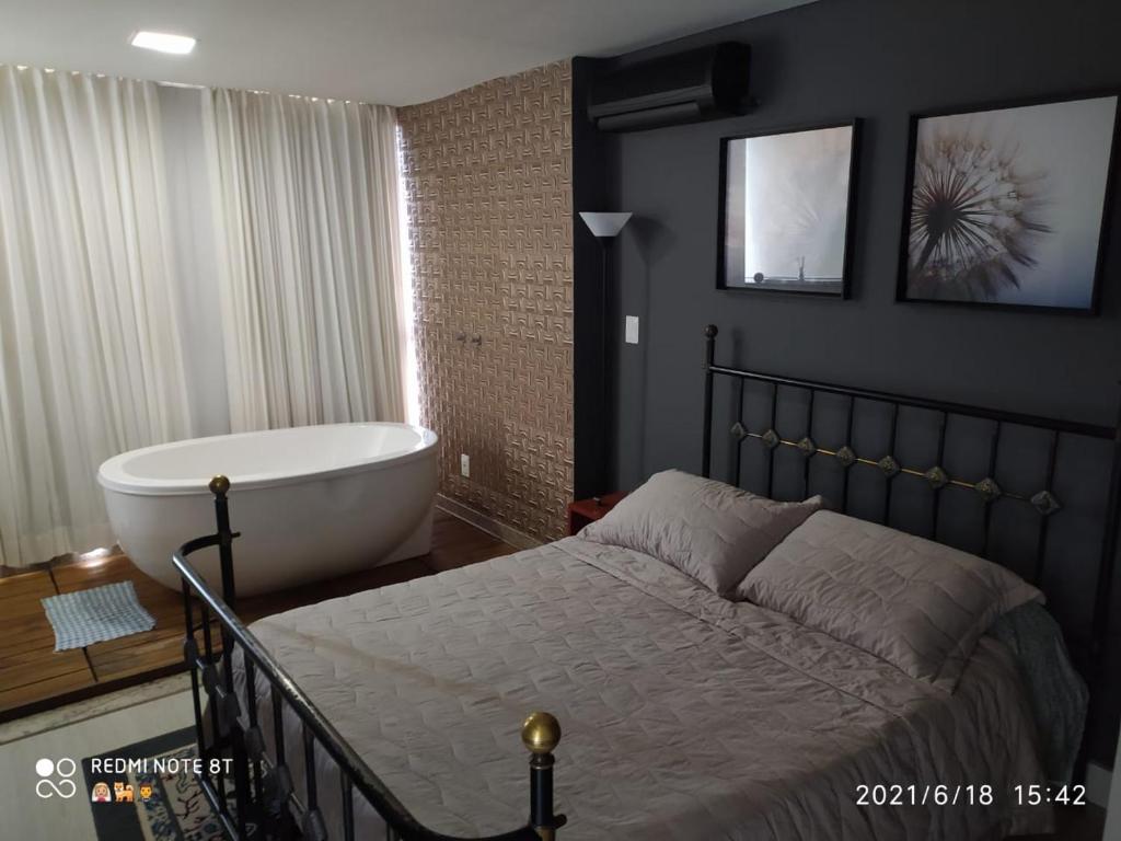 um quarto com uma banheira e uma cama e uma banheira em Loft Espaço Vila da Serra em Nova Lima