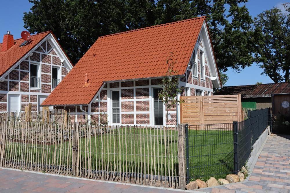 een huis met een oranje dak en een hek bij Ferienhaus-im-Angerdorf in Cuxhaven