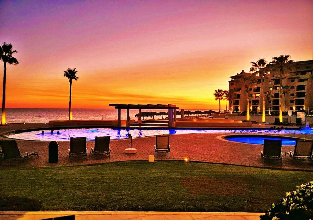 a swimming pool with a sunset in the background at Right on the Beach! Ground Floor Princesa E104 in Puerto Peñasco