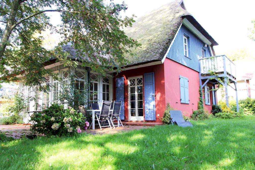 ein rotes und blaues Haus mit Stühlen im Hof in der Unterkunft Darßer Landhaus in Prerow