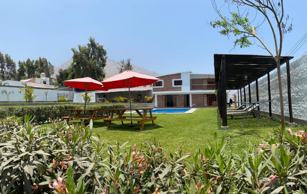 a garden with tables and umbrellas in front of a house at Casa La Parcela en Cieneguilla in Cieneguilla