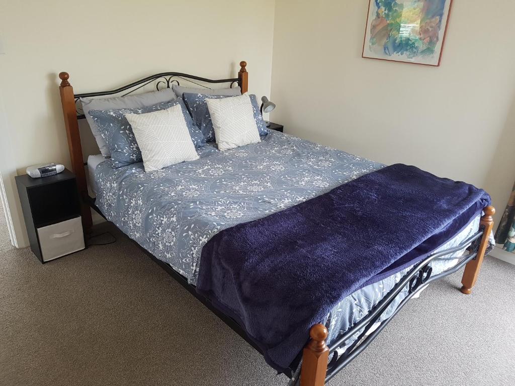 a bedroom with a bed with blue sheets and pillows at Tui Cottage in Hampden